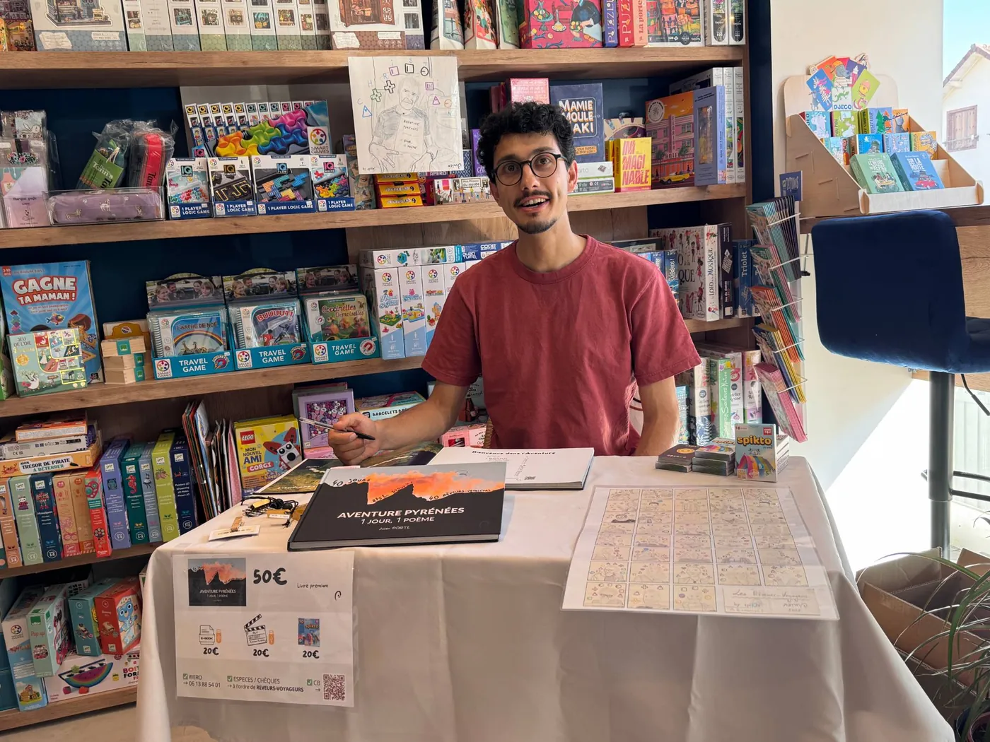Julien Porte signing his book in front of shelves of board games